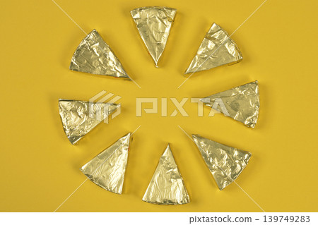 Golden Foil Wrapped Cheese Portions on Yellow Background Golden Foil Wrapped Cheese Portions on Yellow Background 139749283