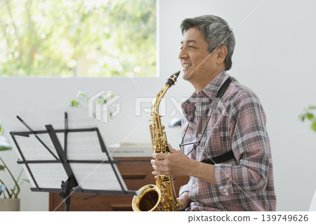 A smiling man in his 60s holding a saxophone. 139749626