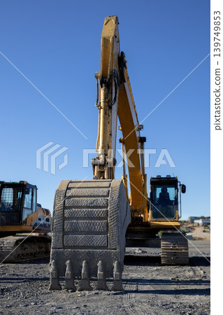 Excavator bucket closeup at construction site against clear blue sky Excavator bucket closeup at construction site against clear blue sky 139749853