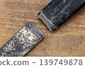 Close-Up of a Broken Iron Sickle Detached from Its Handle, Showing Clear Fracture Point on a Rustic Aged Wooden Surface Background 139749878
