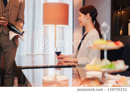 A sommelier introducing wine to female customers A sommelier introducing wine to female customers 139750352