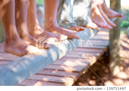 Children, feet and closeup of balance on tree in nature for fun and adventure. Legs, zoom and diverse kids playing outside on wood with stability and support for development and friends bonding Children, feet and closeup of balance on tree in nature for fun and adventure. Legs, zoom and diverse kids playing outside on wood with stability and support for development and friends bonding 139751497
