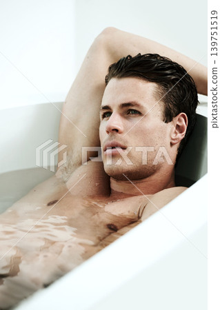 Man, bathtub and face for relax in bathroom with thinking, wellness and contemplating in the morning. Model, person and lying down in bath for self care, grooming and cosmetic routine with topless Man, bathtub and face for relax in bathroom with thinking, wellness and contemplating in the morning. Model, person and lying down in bath for self care, grooming and cosmetic routine with topless 139751519