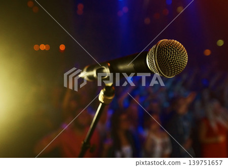 Closeup, microphone and stage performance in theater with audience and sound equipment for concert or singing. Audio, technology and light in dark room with crowd for open mic, karaoke or music event Closeup, microphone and stage performance in theater with audience and sound equipment for concert or singing. Audio, technology and light in dark room with crowd for open mic, karaoke or music event 139751657