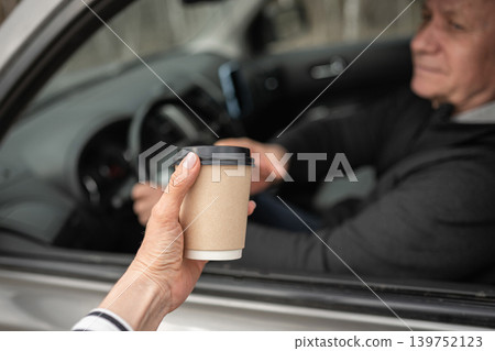 Man Giving Takeaway Coffee Through Car Window Man Giving Takeaway Coffee Through Car Window 139752123