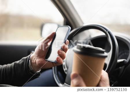 Driver Holding Smartphone And Coffee Cup While Driving 139752130