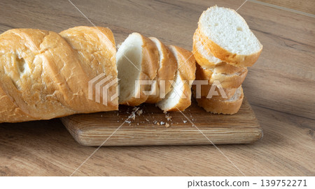 Slices of freshly sliced baguette on a wooden board. Fresh bread sliced. Rustic, handmade rye bread with a golden crust and soft crumb Slices of freshly sliced baguette on a wooden board. Fresh bread sliced. Rustic, handmade rye bread with a golden crust and soft crumb 139752271