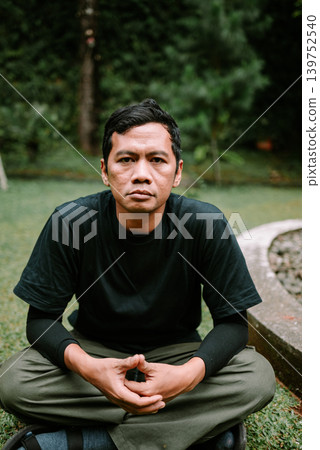 Southeast Asian Man Sitting Cross Legged Looking at Camera Southeast Asian Man Sitting Cross Legged Looking at Camera 139752540
