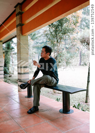 Relaxed Southeast Asian Male Smoking in Cozy Semi Outdoor Environment Relaxed Southeast Asian Male Smoking in Cozy Semi Outdoor Environment 139752549