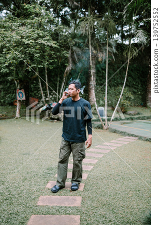 Southeast Asian Man Smoking Outdoors Near Trees and Nature 139752552