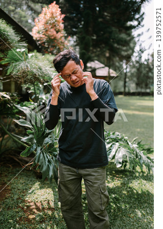 Southeast Asian Man Scratching Itchy Ear Outdoors Southeast Asian Man Scratching Itchy Ear Outdoors 139752571