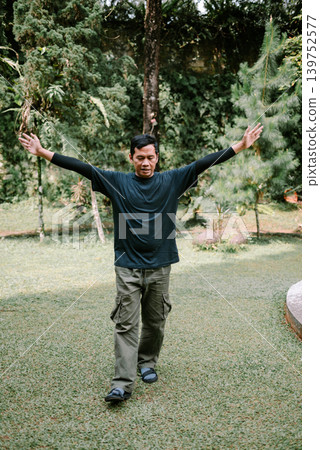 Southeast Asian Man Raising Hands with Happy Expression Outdoors Southeast Asian Man Raising Hands with Happy Expression Outdoors 139752577