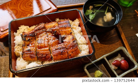 close up of traditional Japanese unagi donburi with grilled eel fillets glazed in sweet soy sauce over rice, served in lacquered box, marinated plum and wasabi on the side with miso soup close up of traditional Japanese unagi donburi with grilled eel fillets glazed in sweet soy sauce over rice, served in lacquered box, marinated plum and wasabi on the side with miso soup 139752644