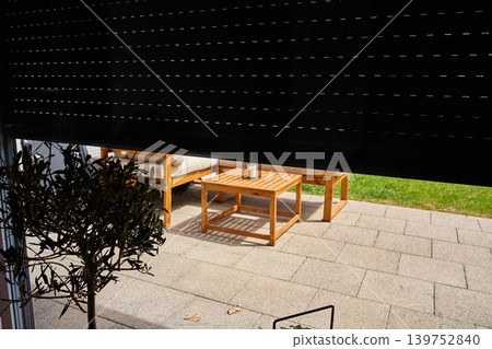 Partially lowered roller shutter over patio door with garden view Partially lowered roller shutter over patio door with garden view 139752840