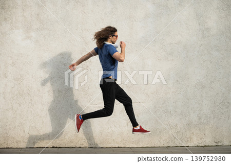 Athletic man jumping with shadow on wall 139752980