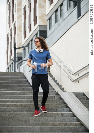 Handsome runner walking down urban stairs Handsome runner walking down urban stairs 139752981