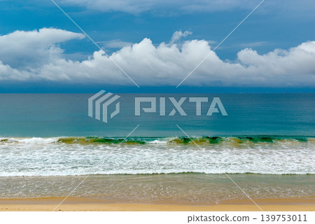 Beautiful sandy beach with turquoise ocean waves and dramatic white clouds on blue sky background Beautiful sandy beach with turquoise ocean waves and dramatic white clouds on blue sky background 139753011