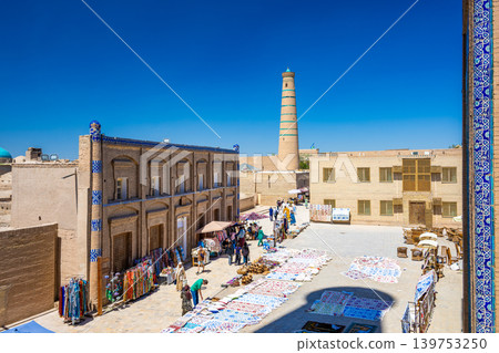 The ancient Silk Road city of Khiva: Colorful souvenirs and minarets line the square. The ancient Silk Road city of Khiva: Colorful souvenirs and minarets line the square. 139753250