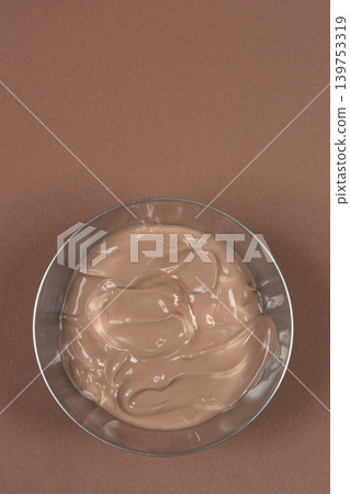 Chocolate pudding in a metal bowl on brown background Chocolate pudding in a metal bowl on brown background 139753319