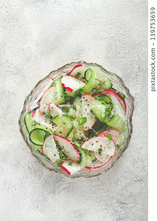 Fresh cucumber and radish salad served in a glass bowl with herbs and dressing on a light background Fresh cucumber and radish salad served in a glass bowl with herbs and dressing on a light background 139753659