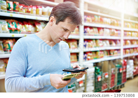 Man with dollars and calculator in store 139753808