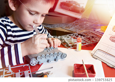 Little boy collects plastic model tank Little boy collects plastic model tank 139753825