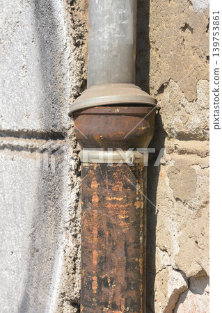 Old rusty downspout on a weathered wall Old rusty downspout on a weathered wall 139753861
