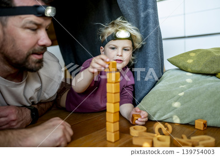 Dad and child building and playing in cozy blanket fort. Dad and child building and playing in cozy blanket fort. 139754003