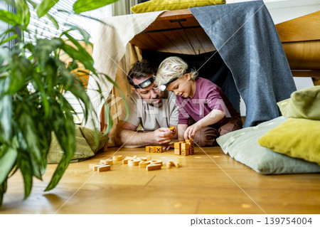 Dad and child building and playing in cozy blanket fort. Dad and child building and playing in cozy blanket fort. 139754004