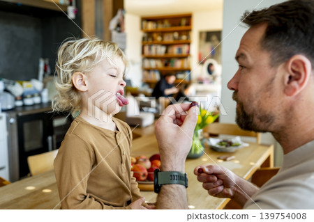 Toddler refusing food offered by father at kitchen. Toddler refusing food offered by father at kitchen. 139754008