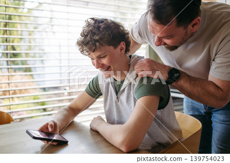Father supporting teenage son at home during everyday moment. Father supporting teenage son at home during everyday moment. 139754023