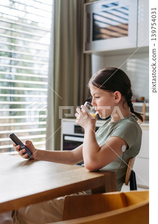 Teen girl checking her blood glucose level in app and drinking water. 139754031
