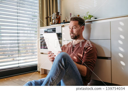 Man using smart home app to control electric window shades indoors. Man using smart home app to control electric window shades indoors. 139754034