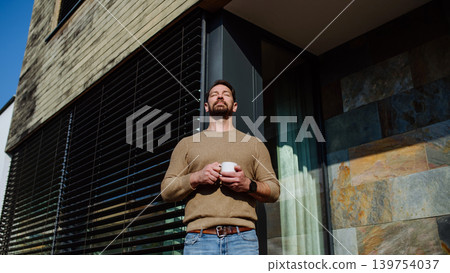 Relaxed man drinking coffee on terrace at home on sunny day. Relaxed man drinking coffee on terrace at home on sunny day. 139754037