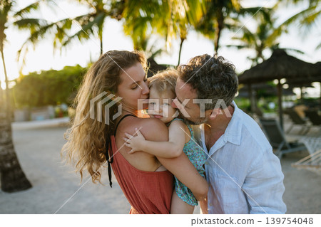 Parents and girl spending summer vacation in tropical beach resort. 139754048