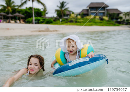 Sisters playing in shallow tropical sea during family beach vacation. Sisters playing in shallow tropical sea during family beach vacation. 139754057