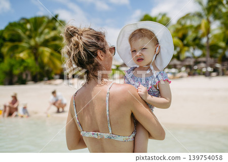 Mother playing in sea water with little daughter. 139754058