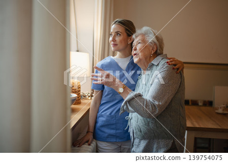 Caring healthcare worker visiting a senior patient at home, hugging her. 139754075