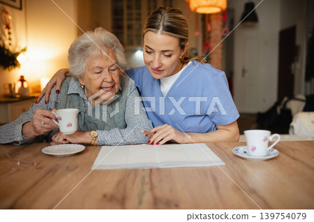 Social worker helping elderly lady with managing her finances, working on financial plan. Social worker helping elderly lady with managing her finances, working on financial plan. 139754079