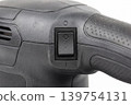 Close up of an electric power tool on off switch and textured handle isolated on white background. Detailed view of control element for repair, maintenance, safety, workshop, and industry concepts. 139754131