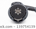Close-up of a random orbital sander pad with mounting holes and central bearing, isolated on white background. Detailed view of an electric woodworking tool for sanding, finishing, repair. 139754139