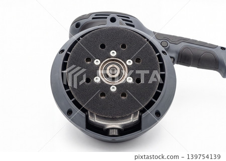 Close-up of a random orbital sander pad with mounting holes and central bearing, isolated on white background. Detailed view of an electric woodworking tool for sanding, finishing, repair. Close-up of a random orbital sander pad with mounting holes and central bearing, isolated on white background. Detailed view of an electric woodworking tool for sanding, finishing, repair. 139754139