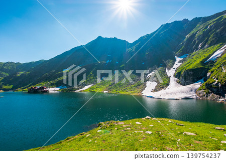 beautiful alpine scenery of fagaras mountains. balea lake in romania mountain landscape. summer weather with clouds on sky. view of rippled water near rocky slope. remote wilderness travel background beautiful alpine scenery of fagaras mountains. balea lake in romania mountain landscape. summer weather with clouds on sky. view of rippled water near rocky slope. remote wilderness travel background 139754237