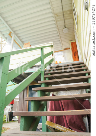 Exterior view of a house with a wooden staircase covered by a rain shelter. Exterior view of a house with a wooden staircase covered by a rain shelter. 139754272