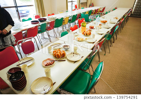 A dining scene with a large group of people gathered around a table of colorful chairs. 139754291