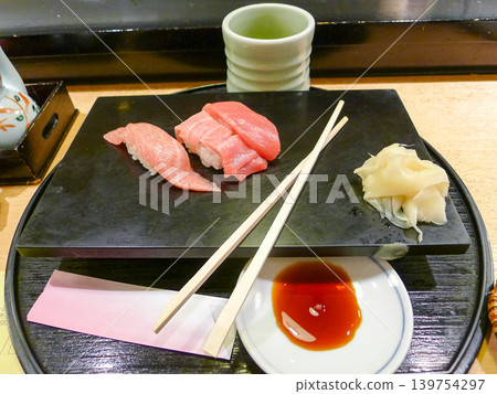 A Japanese dish featuring fresh bluefin tuna sushi and pickled ginger. 139754297