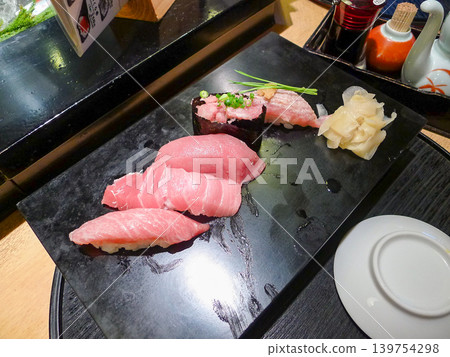 A Japanese culinary experience enjoying a variety of tuna sushi platters and condiments. A Japanese culinary experience enjoying a variety of tuna sushi platters and condiments. 139754298