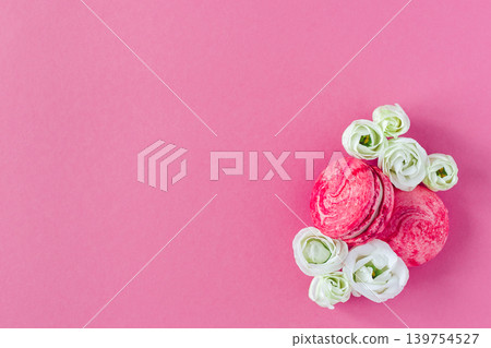 Two pink French macarons with white flowers. Flat lay, place for text. Two pink French macarons with white flowers. Flat lay, place for text. 139754527