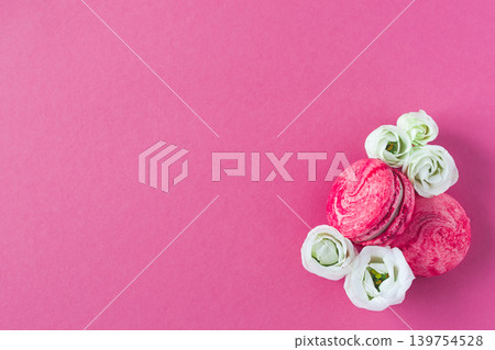 Composition of two pink French macarons and white flowers. Flat lay, place for text. Composition of two pink French macarons and white flowers. Flat lay, place for text. 139754528