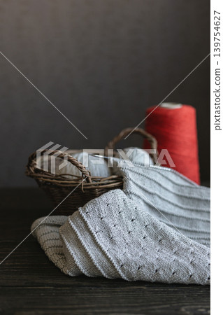 Grey knitting with red yarn in a basket. Grey knitting with red yarn in a basket. 139754627